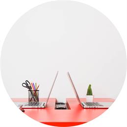 Seitlicher Blick auf einen roten Schreibtisch mit zwei aufgeklappten Laptops