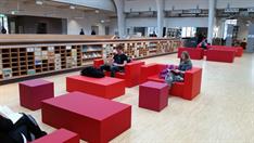 Lounge in der Hochschulbibliothek mit roten Sitzbänken und Tischen