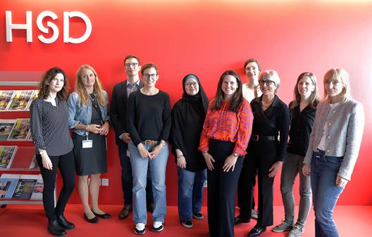 Gruppenfoto von 10 Personen vor einer roten Wand