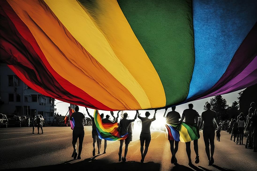 Eine Gruppe von Menschen unterschiedlichen Geschlechts die in Richtung Sonne laufen. Sie ziehen eine riesen große Regenbogenflagge hinter sich her.